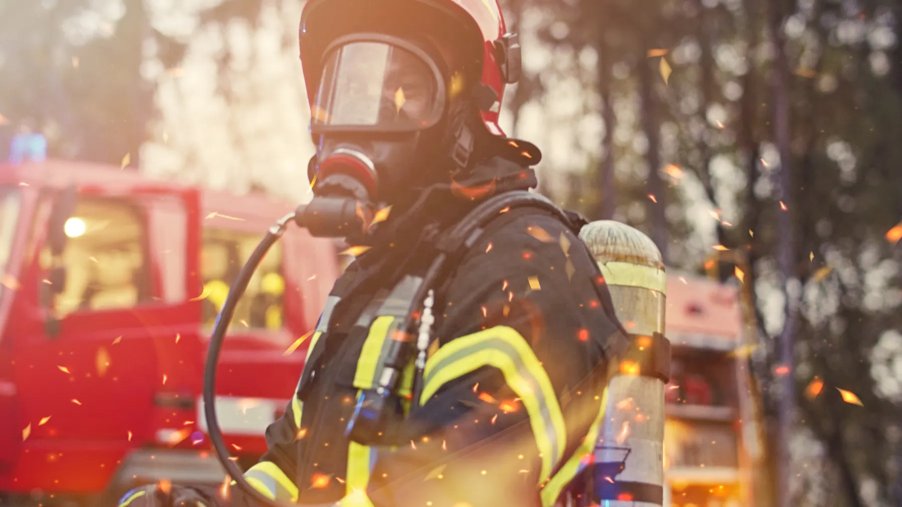 A firefighter in full gear beside an engine