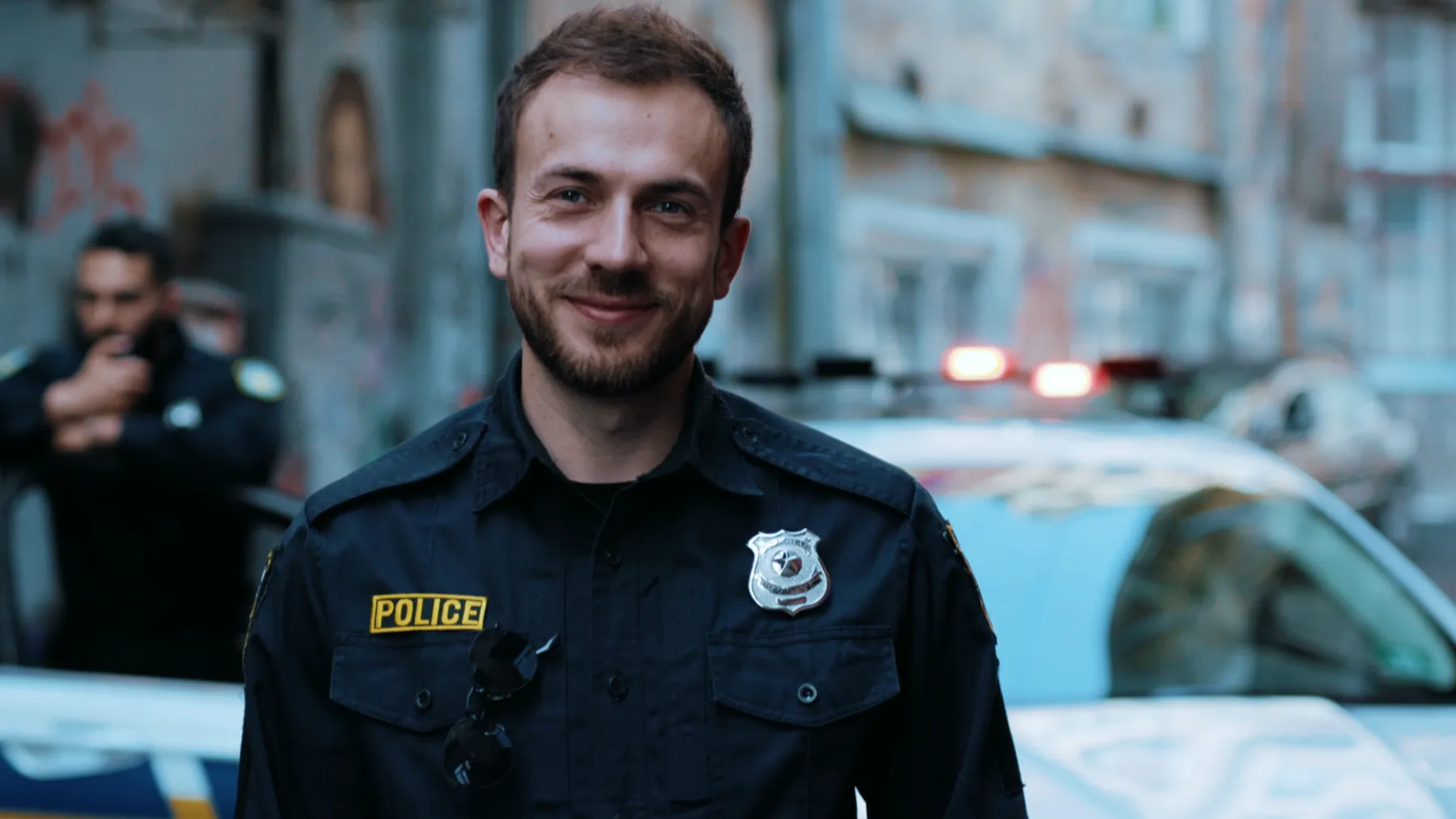 A police officer standing beside a patrol car
