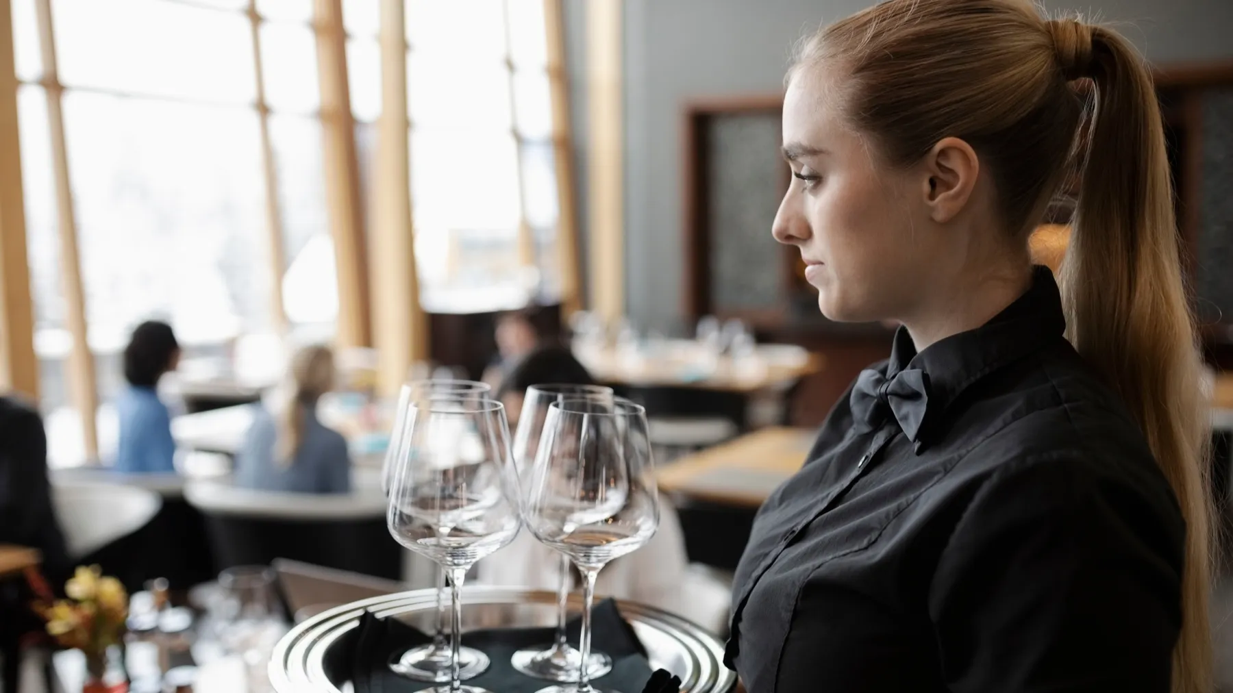 A server carrying a tray of glasses through a restaurant