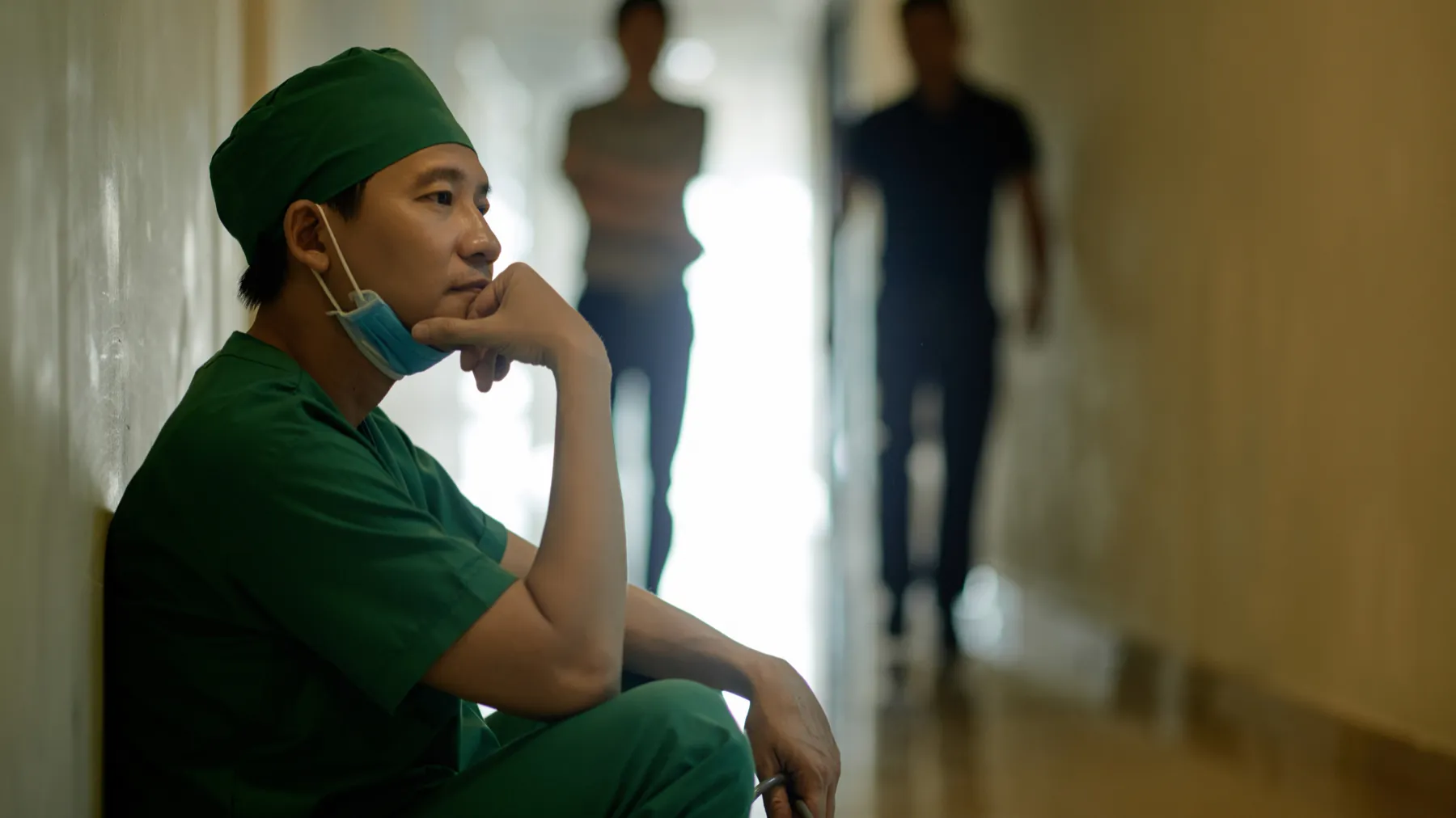 A surgeon resting against a hospital corridor wall