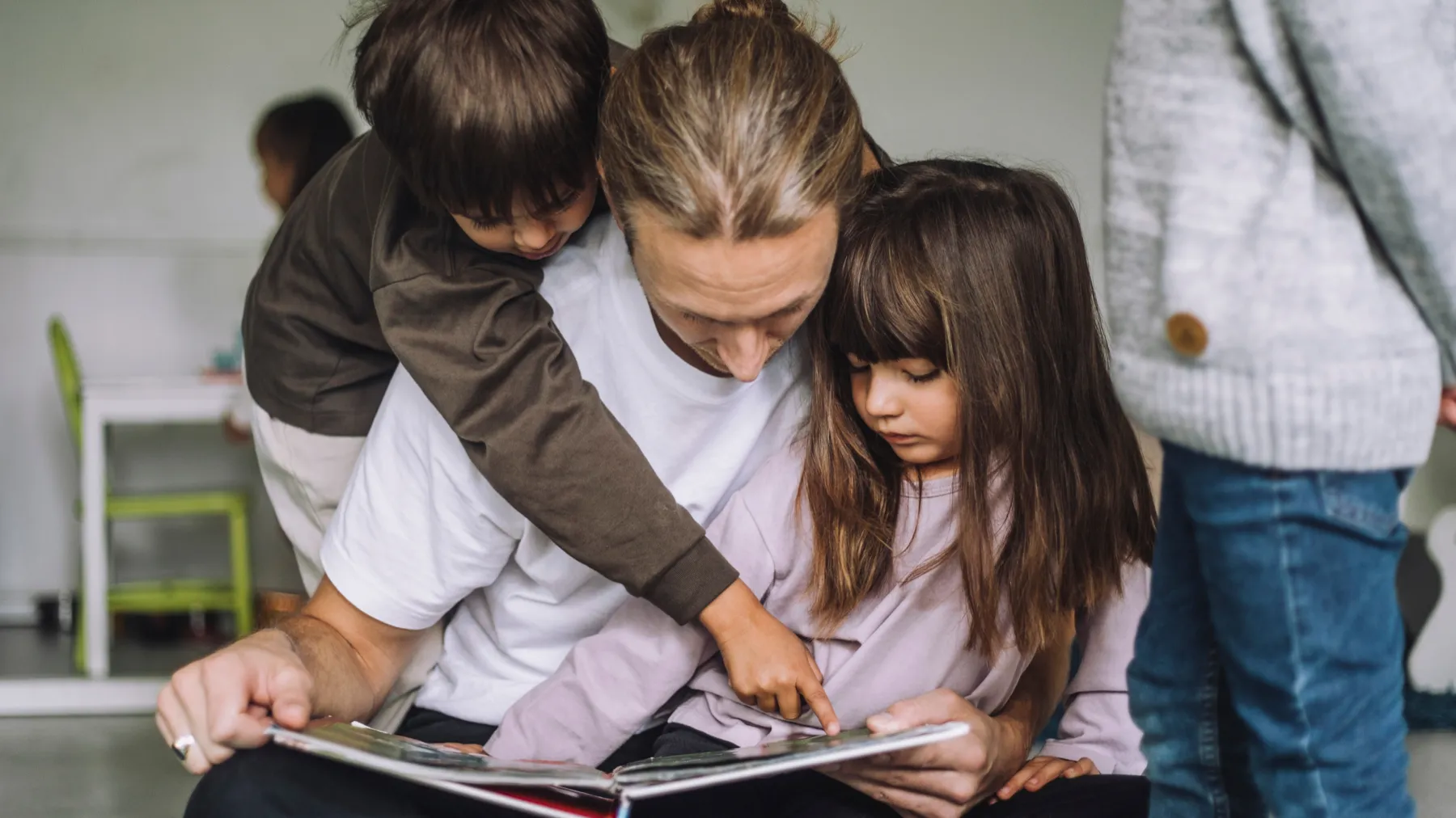 A teacher reading a book with two children